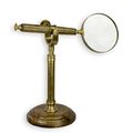 A BRASS MAGNIFYING-GLASS ON A STAND