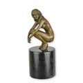 A BRONZE SCULPTURE OF A COWERING NUDE
