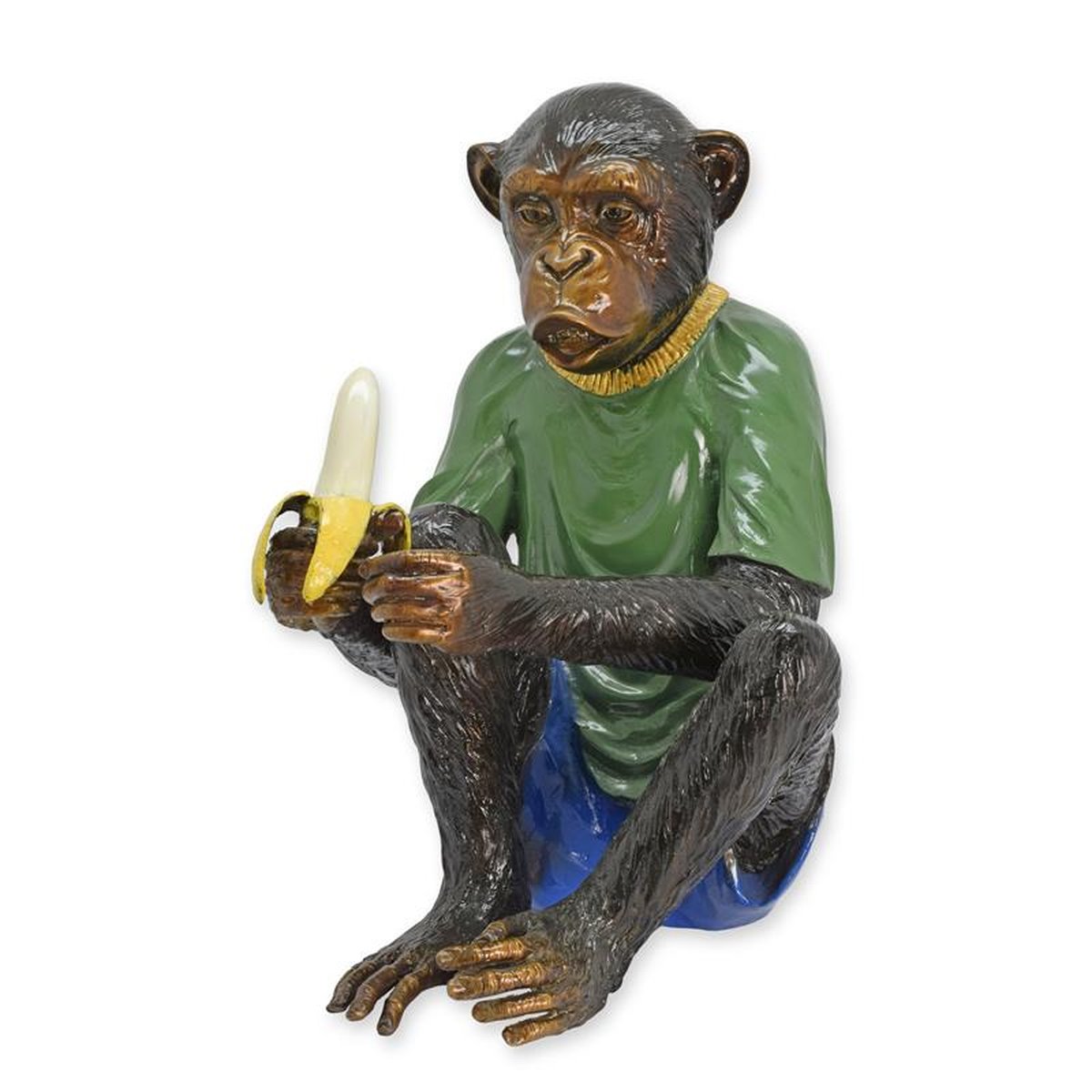 A BRONZE SCULPTURE OF A DRESSED MONKEY EATING A BANANA