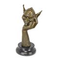 A BRONZE SCULPTURE OF A GOBLIN HEAD RESTING ON HAND