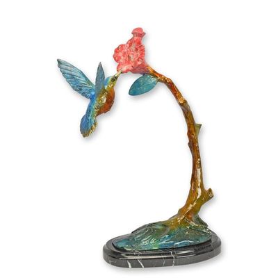 A BRONZE SCULPTURE OF A HUMMING BIRD FEEDING ON A FLOWER