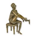 A BRONZE SCULPTURE OF A WOMAN PUTTING ON PANTIES