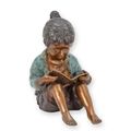 A BRONZE SCULPTURE OF A YOUNG GIRL READING A BOOK