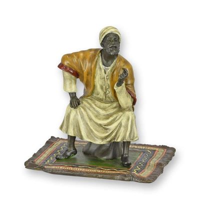 A BRONZE SCULPTURE OF AN ORIENTAL MERCHANT ON CARPET