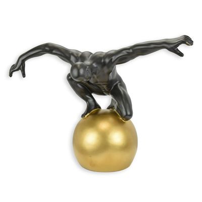 A CERAMIC FIGURINE OF A MALE NUDE ON BALL