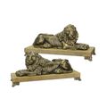 A PAIR OF CAST IRON RECLINING LIONS MOUNTED ON A WOODEN BASE