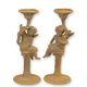 A PAIR OF RUSTY CAST IRON PUTTI CANDLESTANDS