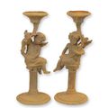 A PAIR OF RUSTY CAST IRON PUTTI CANDLESTANDS