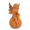 A RUSTY CAST IRON FIGURINE OF A FAIRY SITTING ON BALL
