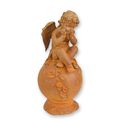 A RUSTY CAST IRON FIGURINE OF A PUTTO SITTING ON BALL
