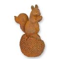 A RUSTY CAST IRON FIGURINE OF A SQUIRREL ON A CHESTNUT